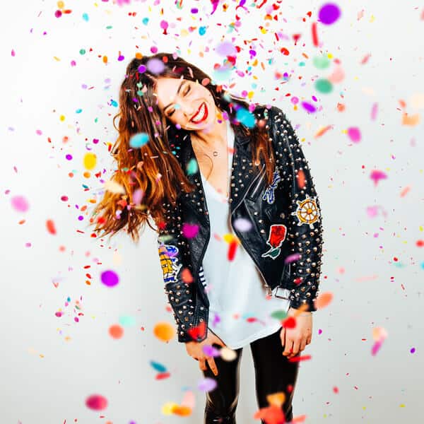 Long haired woman in leather jacket with coloured confetti falling